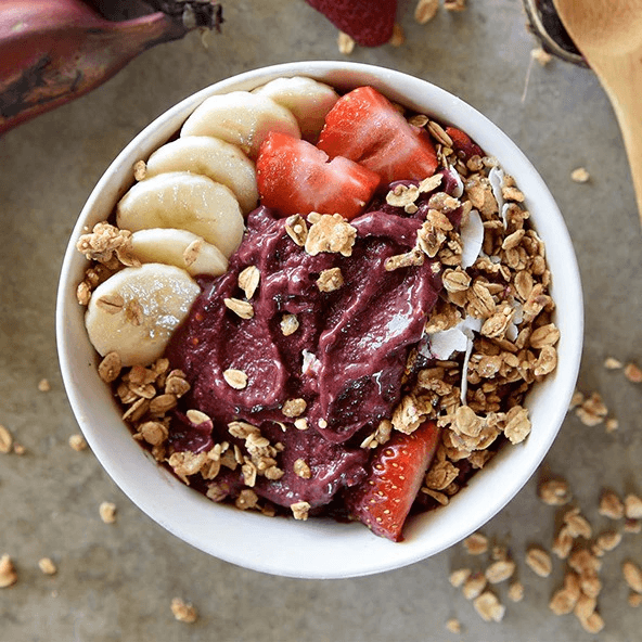 A bowl of Sambazon açaí topped with banana, strawberries, and granola