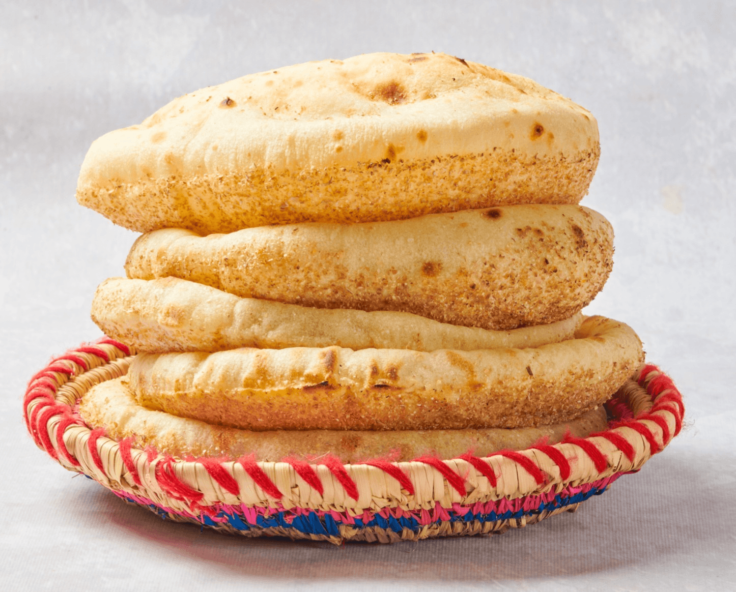 A stack of Egyptian baladi bread in a woven basket